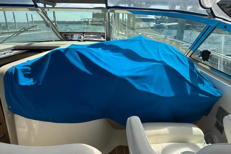 Slide: The Image of 2000 Sea Ray 380 Sundancer cockpit with blue cover, docked by the water. - 4