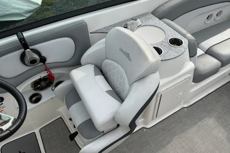 Slide: The Image of 2022 NauticStar 243 DC boat interior with helm seat and cup holders. - 11