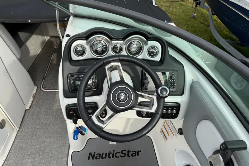 Slide: The Image of 2022 NauticStar 243 DC boat dashboard with steering wheel and gauges. - 14