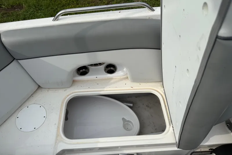 Slide: The Image of 2022 NauticStar 243 DC boat interior storage compartment with gray seating and cup holders. - 9