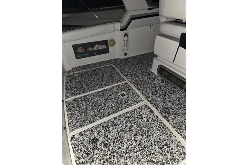 Slide: The Image of 1988 Trojan 8.6 Meter Mid-Cabin boat interior with speckled flooring and seating area. - 12