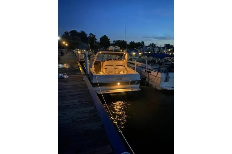 Slide: The Image of 1988 Trojan 8.6 Meter Mid-Cabin boat docked at night with interior lights on. - 4