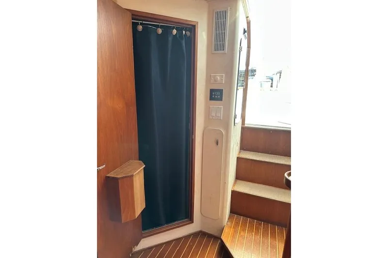 Slide: The Image of Interior of 1992 Tiara Yachts 3600 Open, featuring wooden stairs and a curtained doorway. - 11