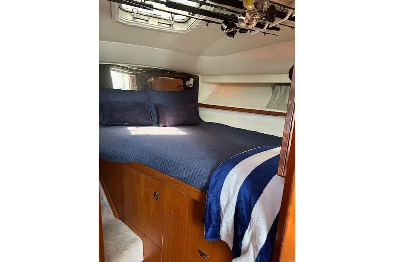Slide: The Image of Cozy cabin interior of 1992 Tiara Yachts 3600 Open with blue bedding. - 13