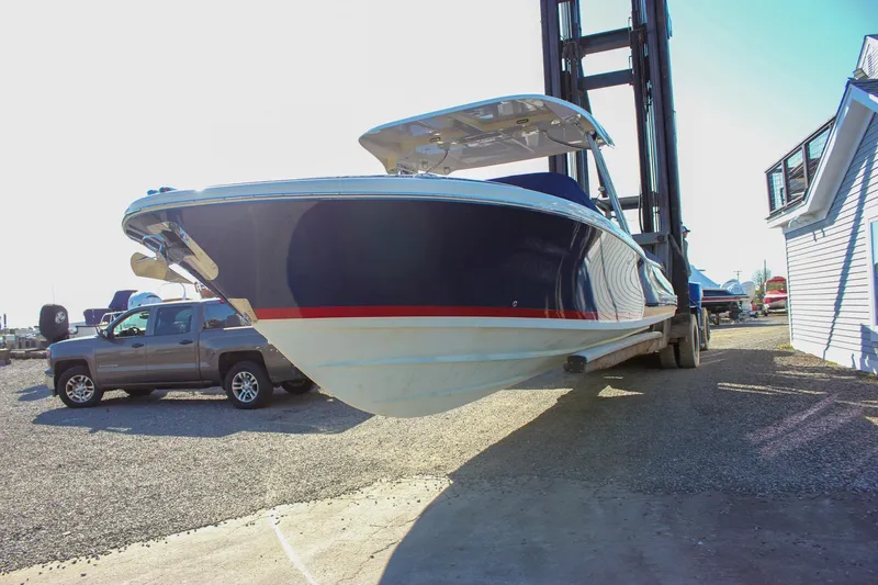 Slide: The Image of 2018 Chris-Craft Calypso 30 boat on lift, blue hull, white and red accents. - 2
