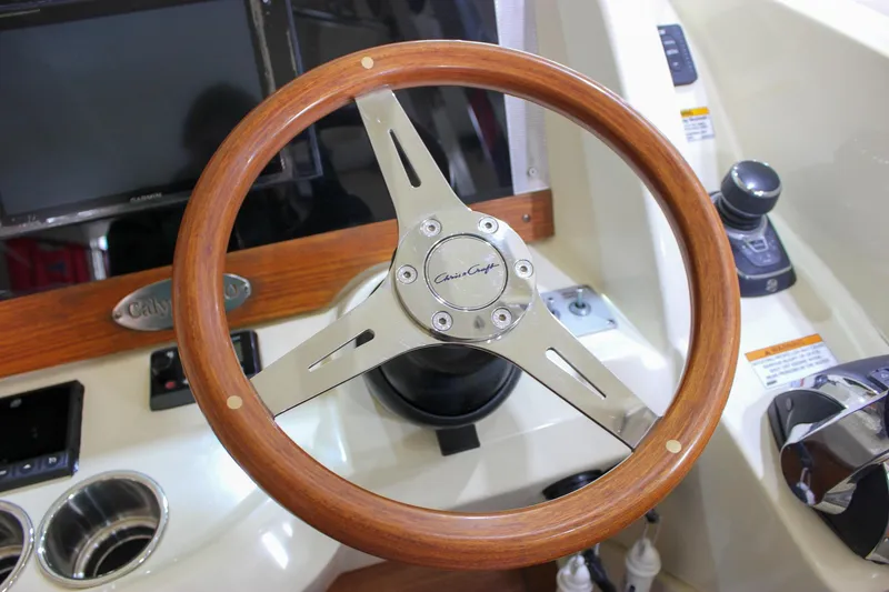 Slide: The Image of 2018 Chris-Craft Calypso 30 helm with wooden steering wheel and control panel. - 42