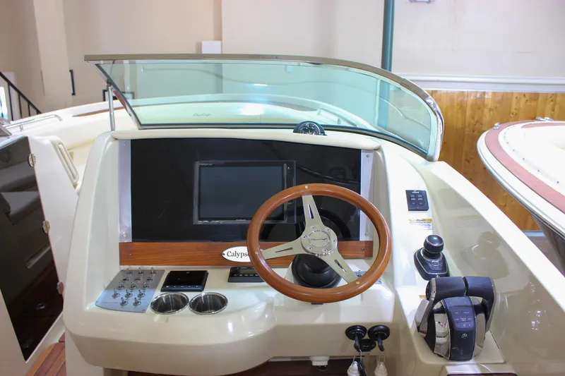 Slide: The Image of 2018 Chris-Craft Calypso 30 helm with wooden steering wheel and modern controls. - 44