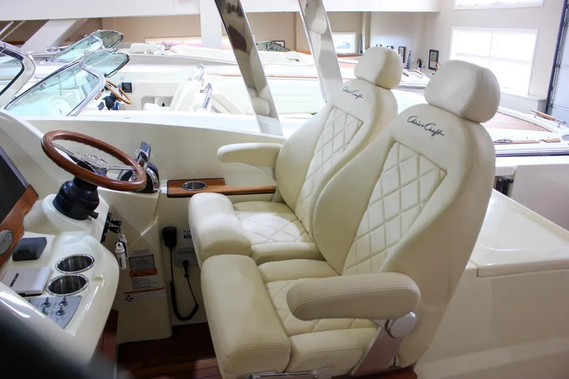 Slide: The Image of 2018 Chris-Craft Calypso 30 interior with luxurious cream seats and wooden steering wheel. - 63