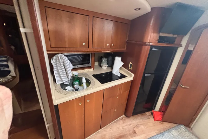 Slide: The Image of 2002 Cruisers Yachts interior kitchen with wooden cabinets, sink, and appliances. - 15