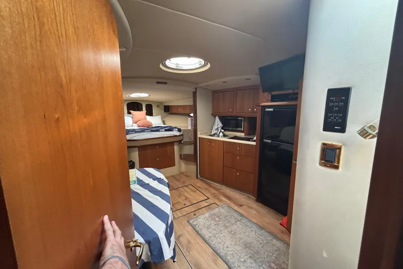 Slide: The Image of Interior of a 2002 Cruisers Yachts, featuring a cozy cabin with kitchenette and bed. - 20