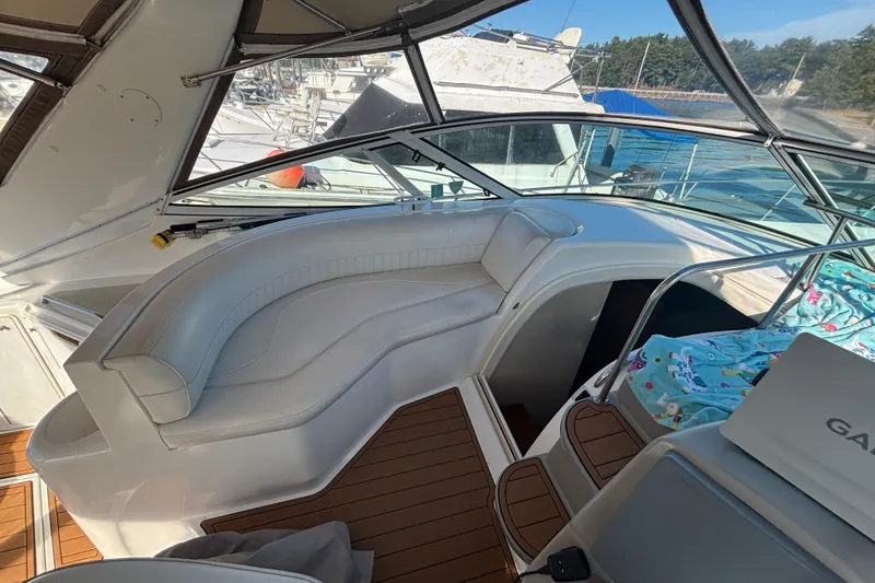 Slide: The Image of 2002 Cruisers Yachts interior with white seating and wooden flooring, docked at marina. - 8