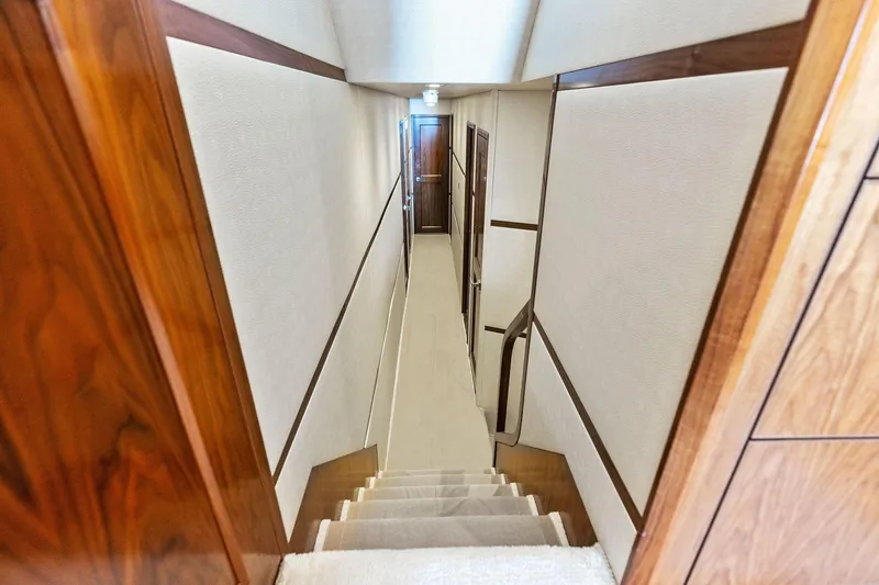 Slide: The Image of Interior hallway of 2018 Viking 80 Convertible yacht with wooden accents and carpeted stairs. - 19