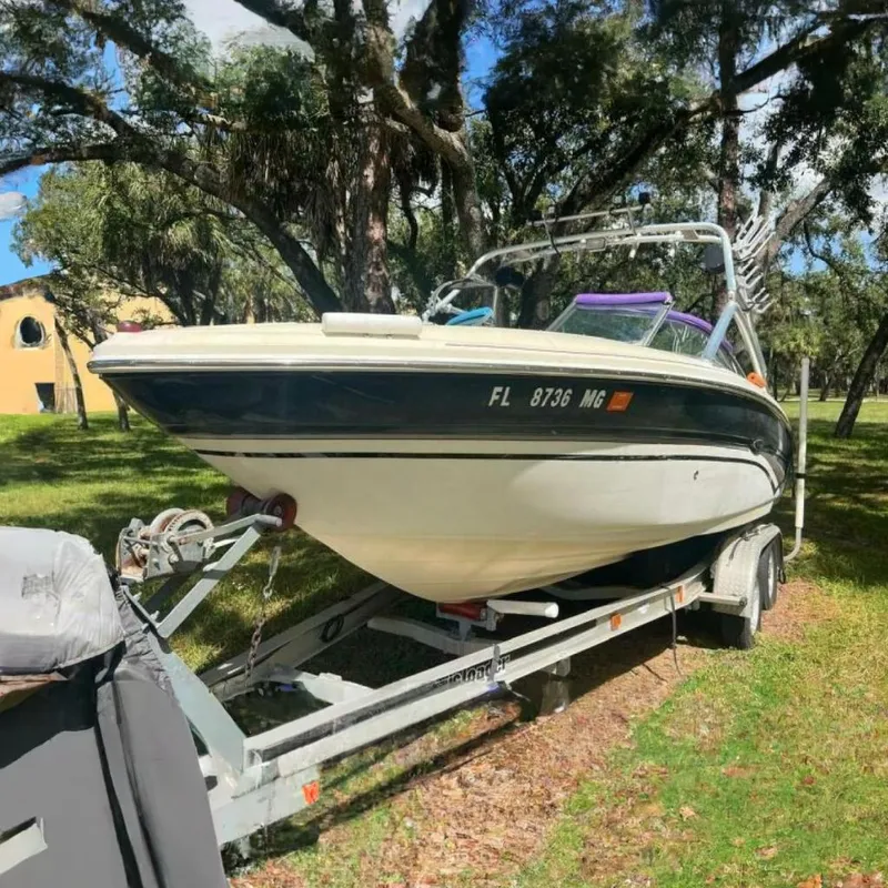 The Image of 2003 Sea Ray 220 Bow Rider on trailer, parked in a wooded area. - 0