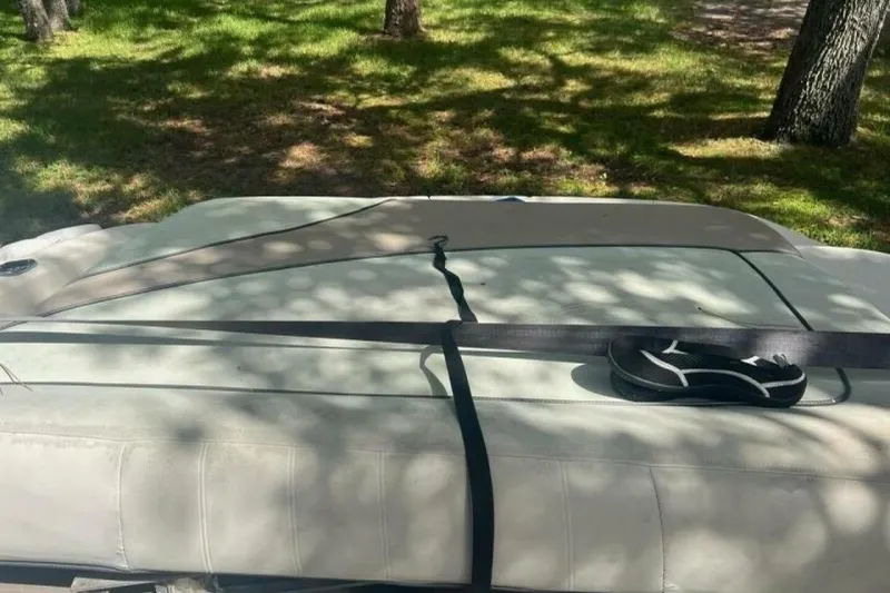 Slide: The Image of 2003 Sea Ray 220 Bow Rider boat interior with seatbelt and flip-flop, shaded by trees. - 15