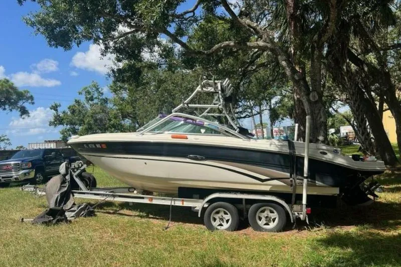 Slide: The Image of 2003 Sea Ray 220 Bow Rider boat on trailer, parked outdoors under trees. - 2