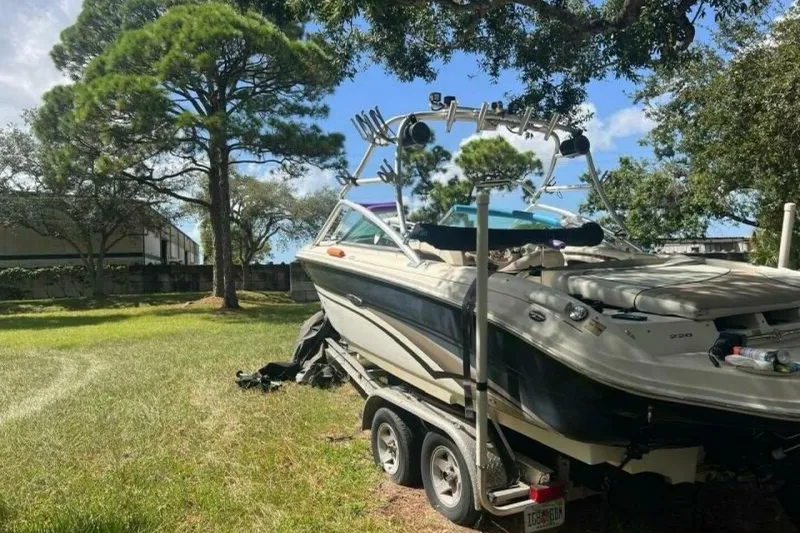 Slide: The Image of 2003 Sea Ray 220 Bow Rider boat on trailer, parked in grassy area with trees. - 22