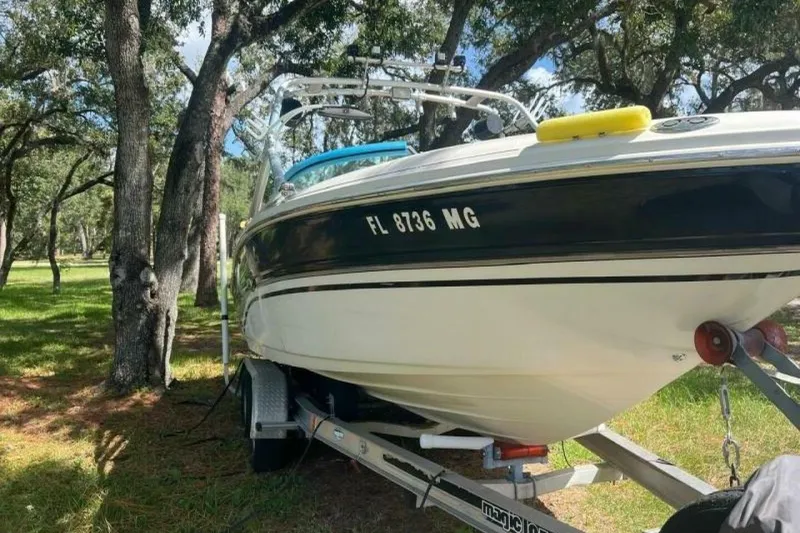 Slide: The Image of 2003 Sea Ray 220 Bow Rider on trailer, parked among trees. - 23