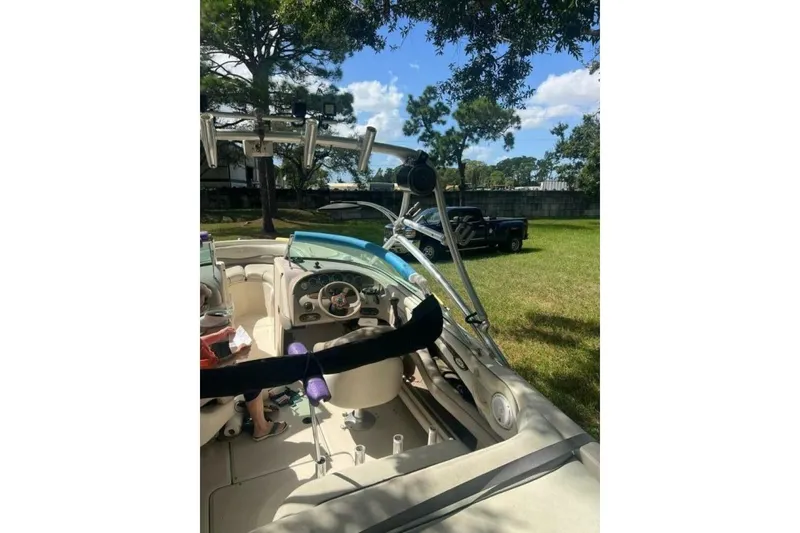 Slide: The Image of 2003 Sea Ray 220 Bow Rider boat interior with steering wheel, parked on grass. - 25