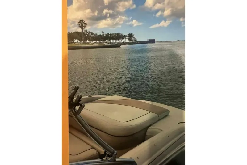 Slide: The Image of 2003 Sea Ray 220 Bow Rider on tranquil water with scenic palm trees and cloudy sky. - 26