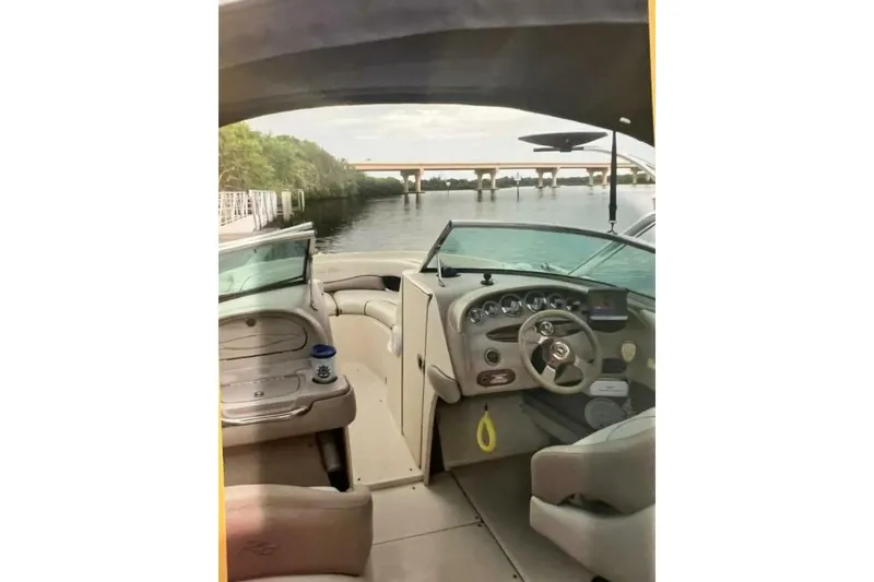 Slide: The Image of 2003 Sea Ray 220 Bow Rider interior with steering wheel, dashboard, and waterway view. - 27