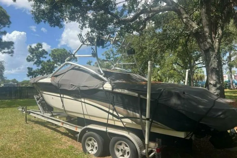 Slide: The Image of 2003 Sea Ray 220 Bow Rider boat on trailer, covered, under trees. - 3