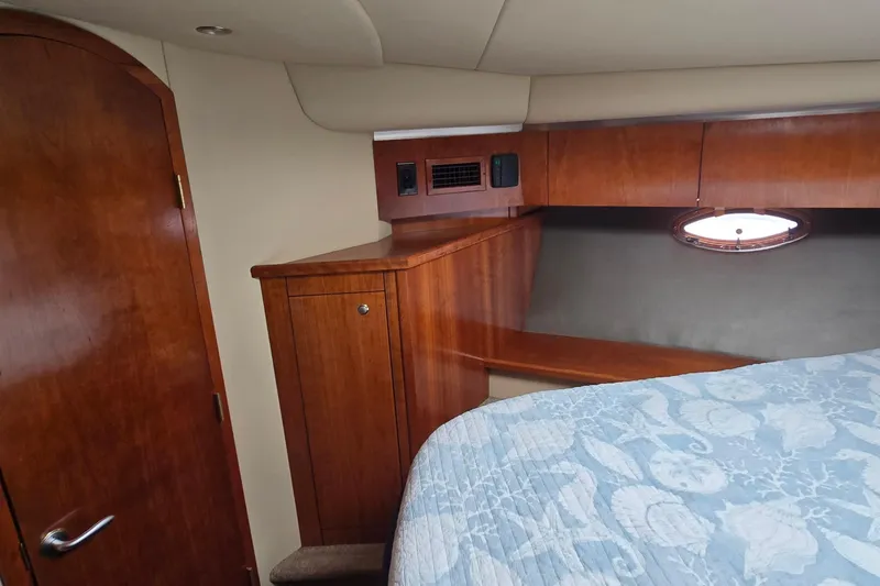 Slide: The Image of 2005 Cruisers Yachts 500 Express cabin interior with bed, wood paneling, and porthole window. - 32