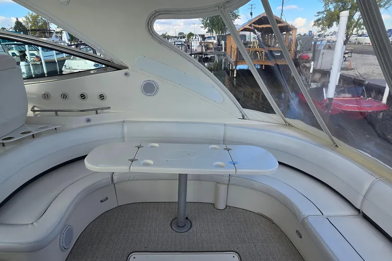 Slide: The Image of 2005 Cruisers Yachts 500 Express interior with white seating and sunflowers, under a clear blue sky. - 16