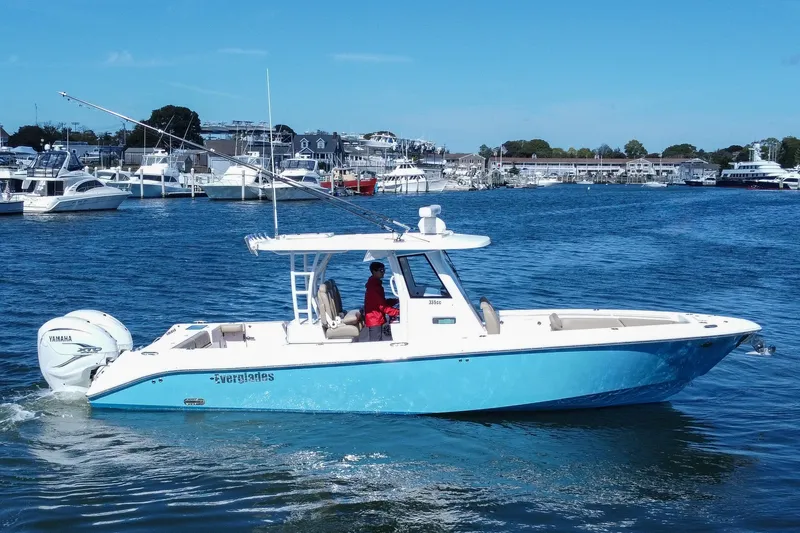 Slide: The Image of 2023 Everglades 335 Center Console boat cruising in a marina with Yamaha engines. - 2