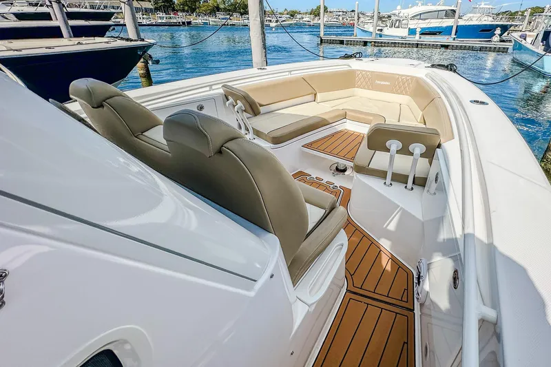Slide: The Image of 2023 Everglades 335 Center Console boat with luxurious seating and teak flooring at a marina. - 25