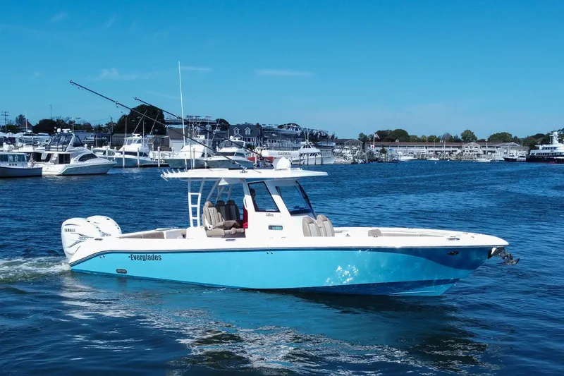Slide: The Image of 2023 Everglades 335 Center Console boat cruising in a marina with clear blue skies. - 3