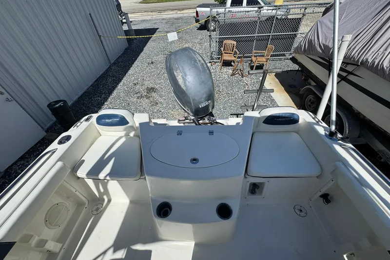 Slide: The Image of 2004 Hydra-Sports Lightning 202 DC boat interior with seating and motor, parked outdoors. - 13