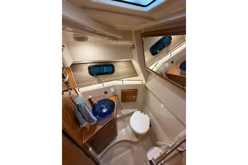Slide: The Image of 2025 Ranger Tugs R-27 boat bathroom with modern fixtures and blue sink. - 10