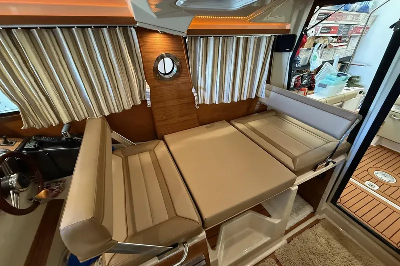 Slide: The Image of Interior of 2025 Ranger Tugs R-27 with convertible seating and striped curtains. - 11