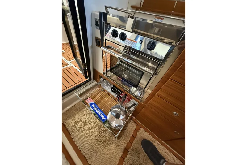 Slide: The Image of 2025 Ranger Tugs R-27 interior kitchen with stainless steel oven and storage drawer. - 15