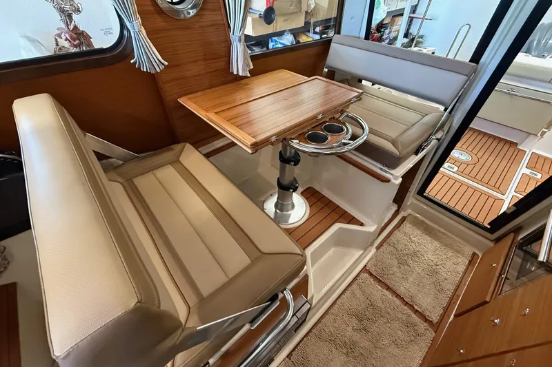 Slide: The Image of 2025 Ranger Tugs R-27 interior with seating, table, and wood accents. - 16