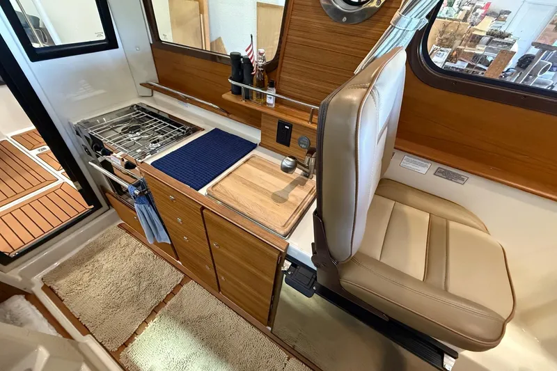 Slide: The Image of 2025 Ranger Tugs R-27 interior galley with stove, sink, and seating. - 7