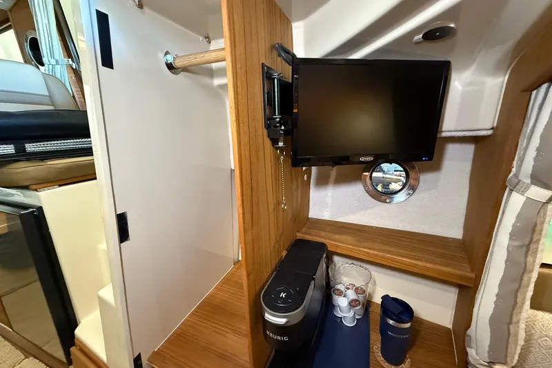 Slide: The Image of 2025 Ranger Tugs R-27 interior with TV, coffee maker, and storage space. - 8