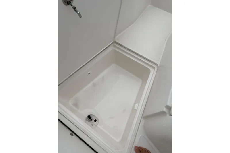 Slide: The Image of 2019 Release 210 RX boat storage compartment with drain plug and white interior. - 10