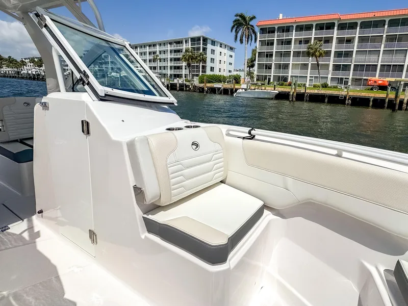 Slide: The Image of 2025 Edgewater 262 CX boat interior with white seating, dockside view. - 18