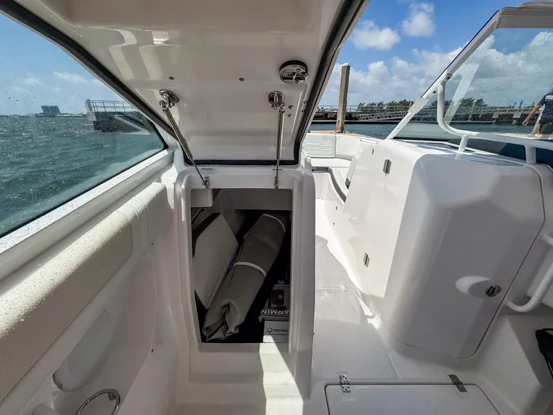 Slide: The Image of 2025 Edgewater 262 CX boat interior with open storage compartment, docked by the water. - 29