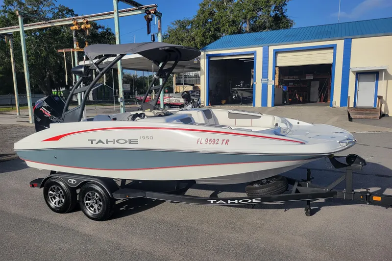 The Image of 2023 Tahoe 1950 boat on trailer, parked outside a blue and white building. - 1