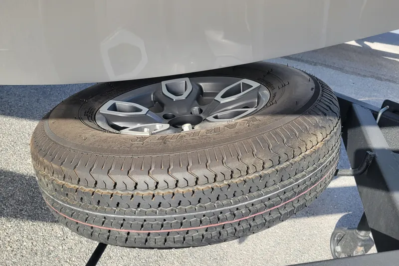 Slide: The Image of Spare tire mounted under a 2023 Tahoe 1950 vehicle on a trailer. - 21