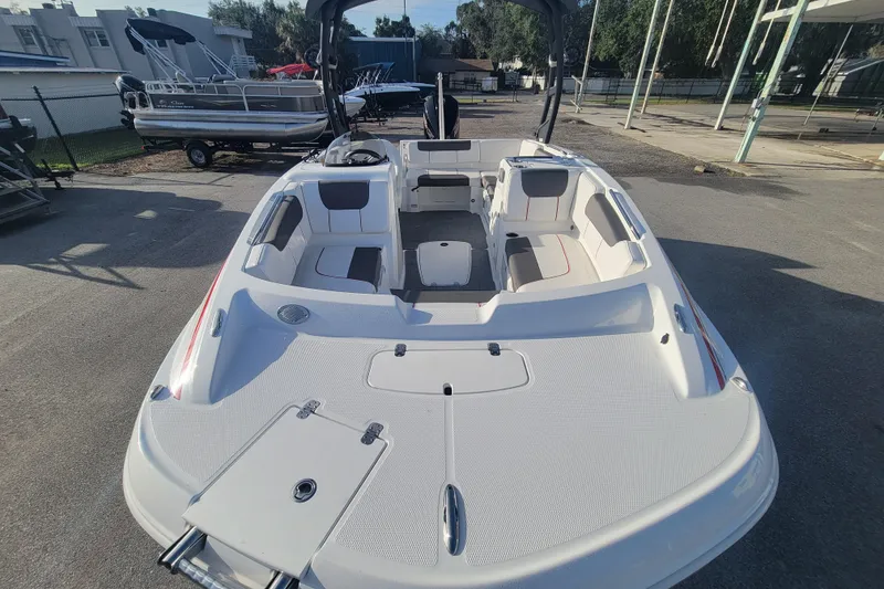 Slide: The Image of 2023 Tahoe 1950 boat interior with seating and storage, parked outdoors. - 6