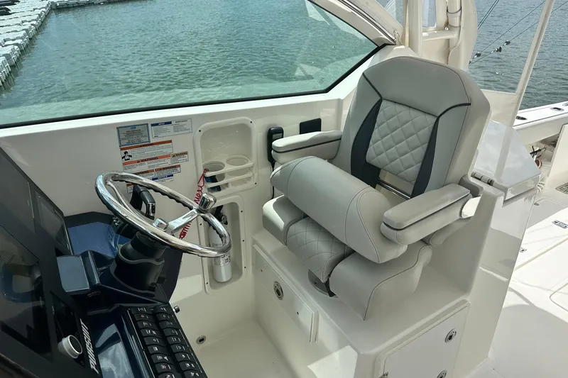 Slide: The Image of 2023 Pursuit DC 295 Dual Console helm with luxury seating and steering wheel. - 12