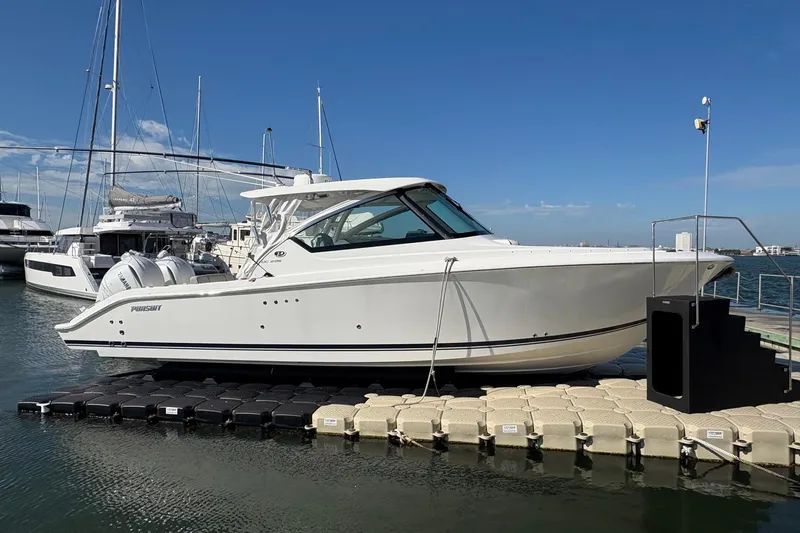 Slide: The Image of 2023 Pursuit DC 295 Dual Console boat docked at marina under clear blue sky. - 4
