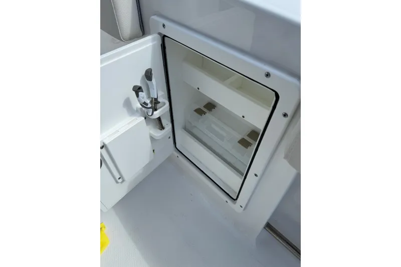 Slide: The Image of 2024 Sea Hunt Gamefish 27 Forward Seating storage compartment with open door and tool holder. - 11