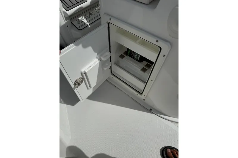 Slide: The Image of 2024 Sea Hunt Gamefish 27 Forward Seating storage compartment with open door, showcasing interior space. - 13