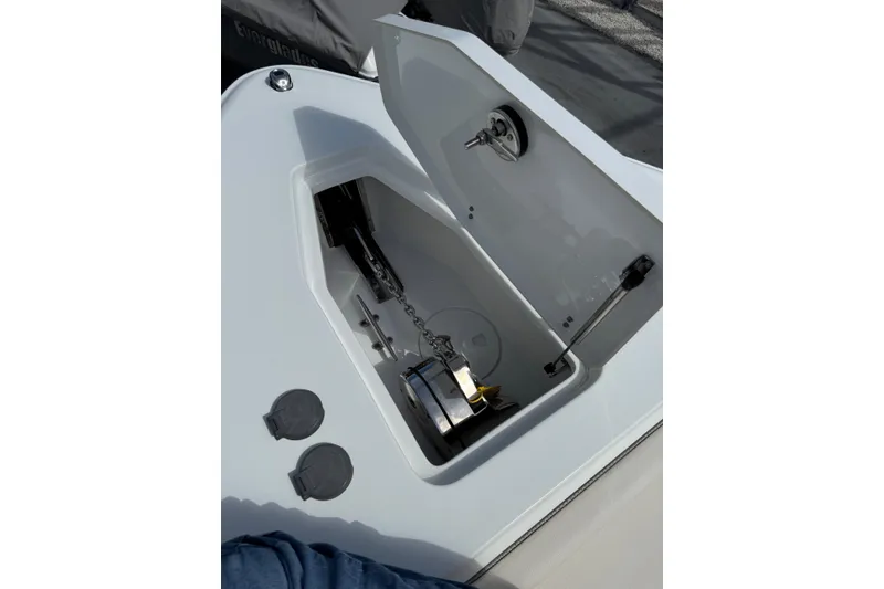 Slide: The Image of 2024 Sea Hunt Gamefish 27 anchor compartment with open hatch, showcasing storage and chain mechanism. - 21