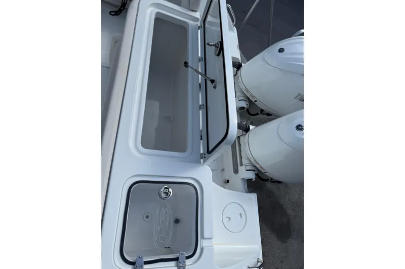 Slide: The Image of 2024 Sea Hunt Gamefish 27 boat with open storage compartment and dual outboard engines. - 7