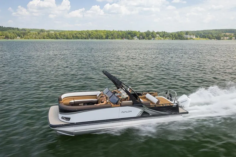 Slide: The Image of 2026 Avalon LSZ CRB pontoon boat cruising on a scenic lake under a clear sky. - 5